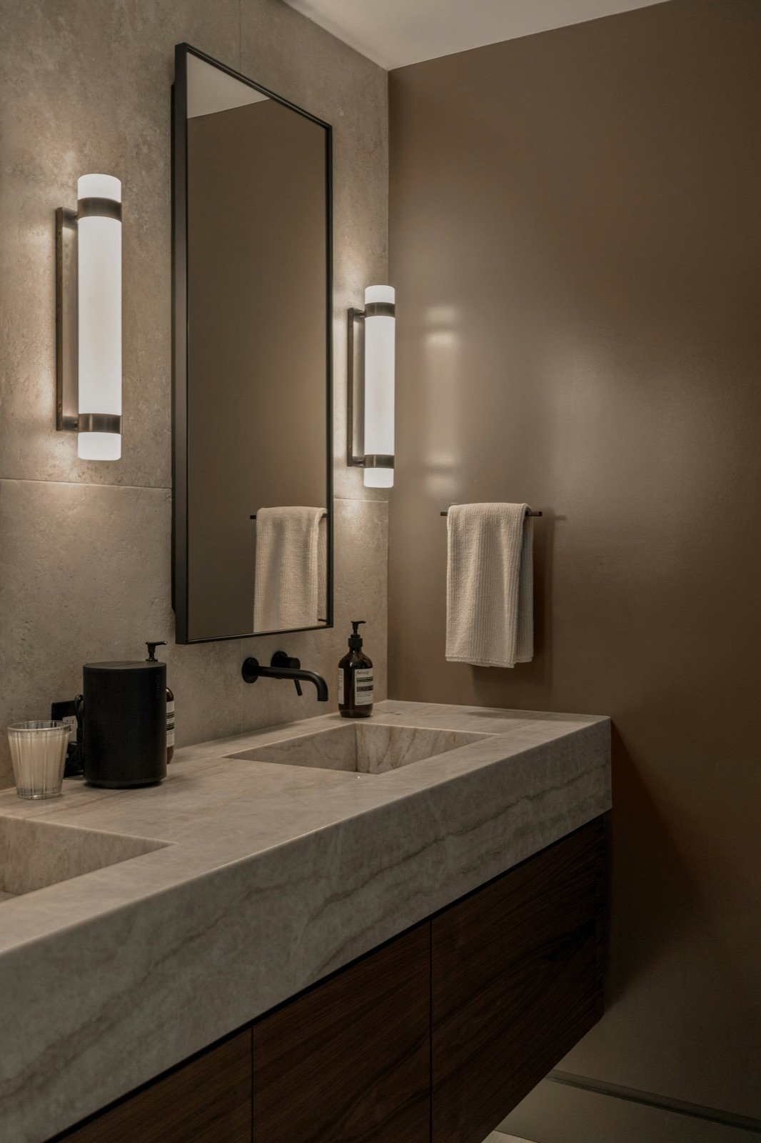 A bathroom vanity mirror flanked by two wall sconces on either side